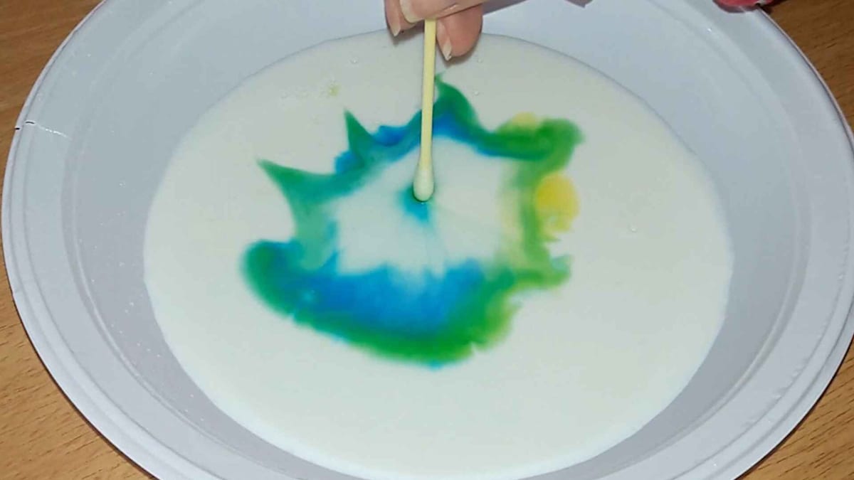 Swirls of food coloring spreading across the surface of milk in the colorful milk experiment