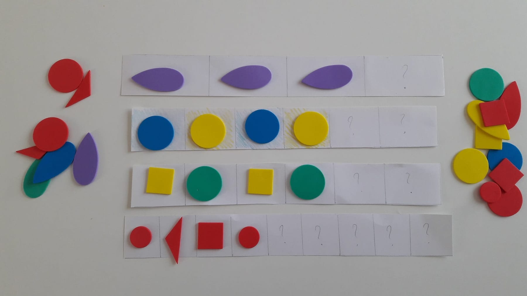 Colorful felt shapes laid out in a repeating pattern for a child to continue